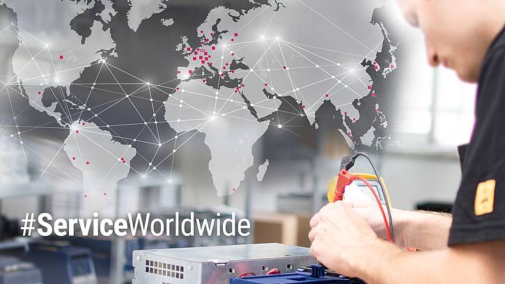 world map with the KEB Automation Site and Partner Locations as pinpoints with a service technician in the n the foreground, testing a frequency inverter