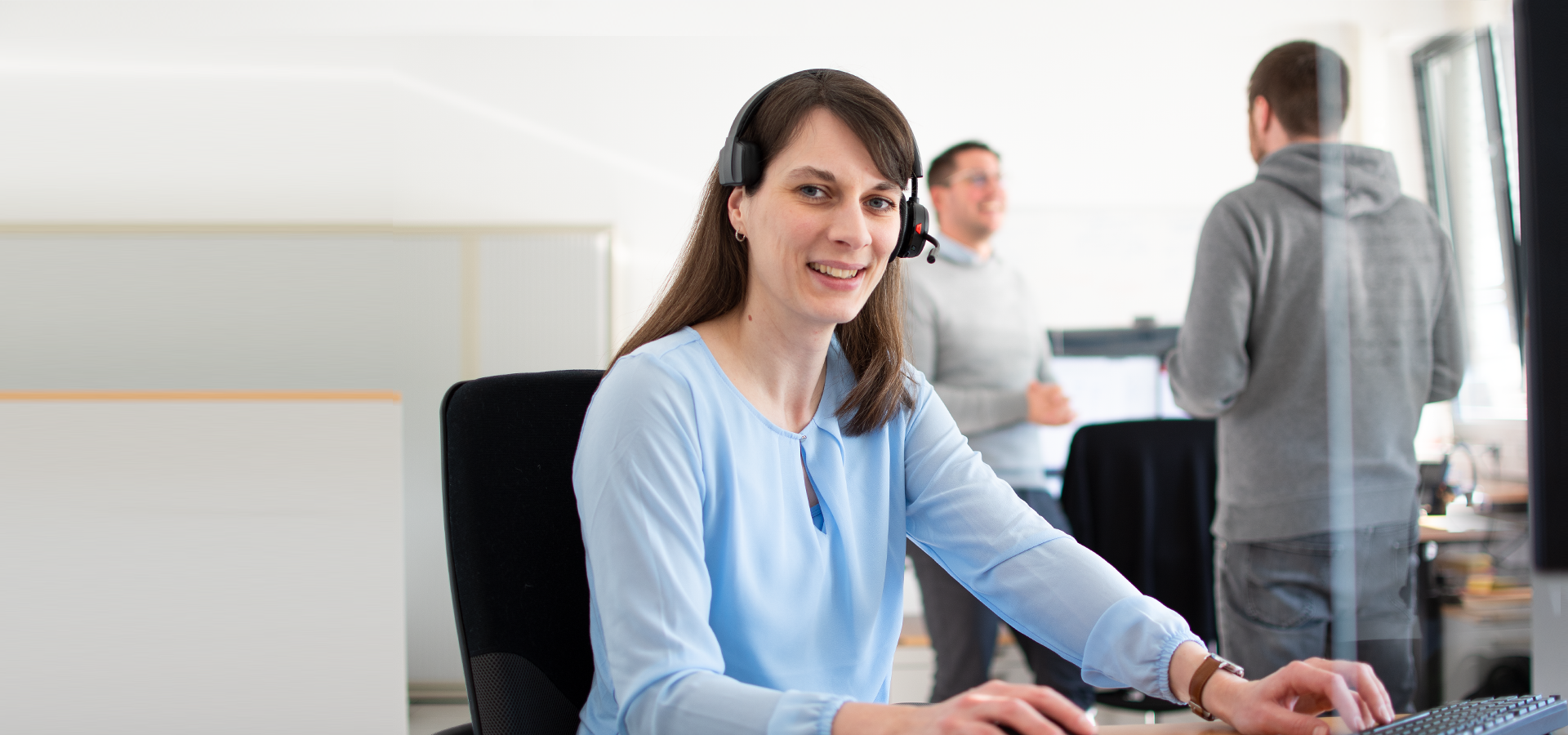 A woman with a headset works at her desk