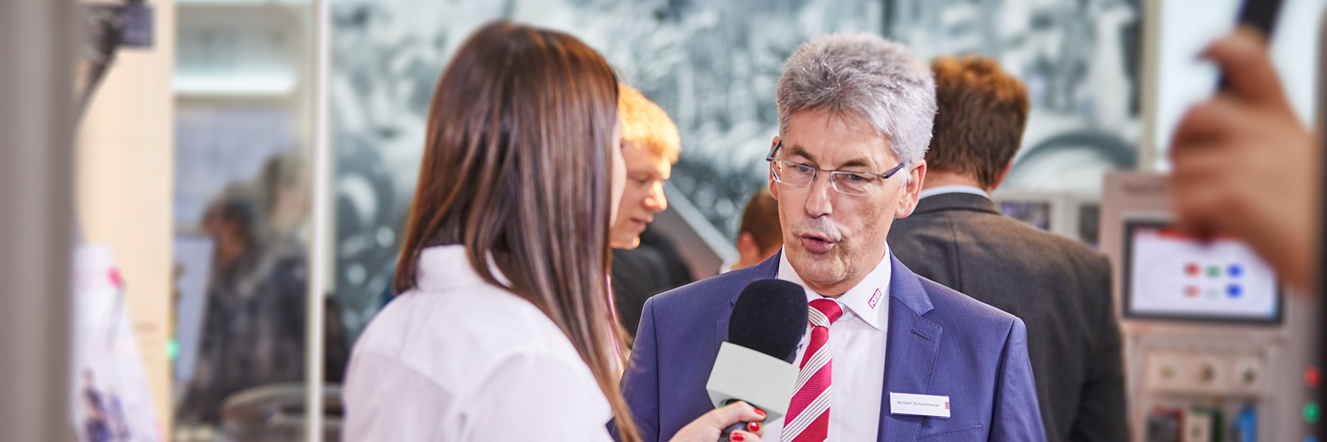 Woman interviews man at trade fair stand